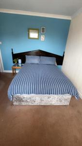 Una cama en un dormitorio con una pared azul. en QueensBerry Annan, en Annan 1 foto más