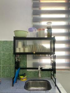 a kitchen with a sink and a shelf with dishes at Obah Homestay Kota Bharu in Kota Bharu