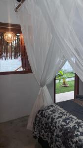 a bed with a canopy in a room with a window at Suítes Independentes em Trancoso in Trancoso