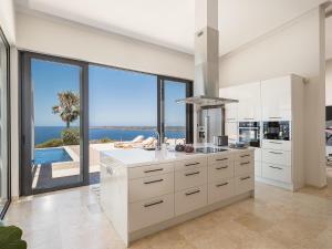 a white kitchen with a view of the ocean at Villa Jamila by Cura Villas Collection in Kalathas