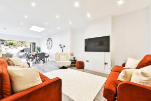 a living room with two orange couches and a tv at Stylish House Near Wembley Stadium in London