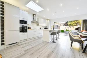 a kitchen with white cabinets and a table and chairs at Stylish House Near Wembley Stadium in London