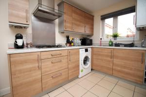 a kitchen with wooden cabinets and a washing machine at Alicia's Way by Tŷ SA in Newport +11 photos