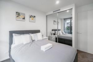 Schlafzimmer mit einem großen weißen Bett und einem Spiegel in der Unterkunft Modern 2Br Ground Level City Retreat with Parking in Braddon
