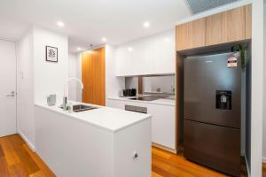 eine Küche mit einem Edelstahlkühlschrank und weißen Schränken in der Unterkunft Modern 2Br Ground Level City Retreat with Parking in Braddon + 7 Fotos