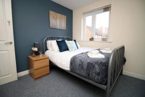 a bedroom with a bed with blue walls and a window at Alicia's Way by Tŷ SA in Newport