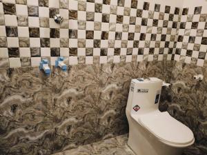 a bathroom with a toilet and a tiled wall at Rudraksha RESIDENCY in Tiruvannāmalai