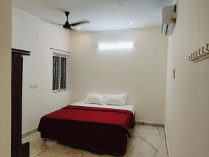 a bed in a white room with a red blanket at Rudraksha RESIDENCY in Tiruvannāmalai