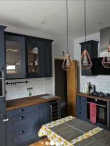 a kitchen with blue cabinets and a table in it at The Cozy Double Retreat in London