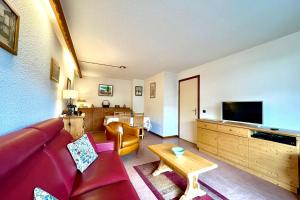 a living room with a red couch and a tv at Cœur Combloran in Combloux
