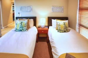 two beds in a small room with a night stand at Ellefsen Golf Suite 115, Langebaan, 4-sleeper in Langebaan +28 photos