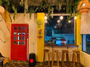 a bar with stools and a red door in a room at The Commune Varanasi in Varanasi