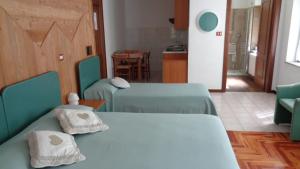 una camera con due letti verdi e una cucina di Mont Gelé a Ollomont