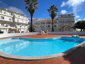 a large swimming pool in front of a building at Elegant 3-bed family beach house with large pool area in Praia da Areia Branca