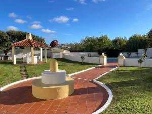 a garden with a table and a gazebo at Elegant 3-bed family beach house with large pool area in Praia da Areia Branca