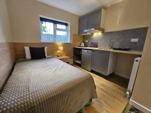 a small bedroom with a bed and a kitchen at The Abbey House Hotel in Reading