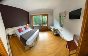 a hotel room with a bed and a desk at Hotel Els Avets in Sorpe