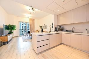 an open kitchen with white cabinets and a living room at Yas Island 2BR | Pool | Near Ferrari World & Mall in Abu Dhabi