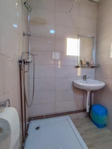 a white bathroom with a sink and a shower at Cabana Georgiana Dealu Negru in Dealu Negru