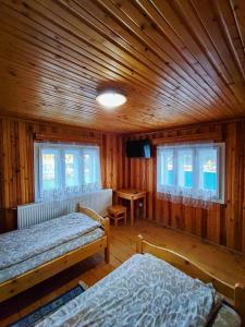 a bedroom with two beds and a wooden ceiling at Cabana Georgiana Dealu Negru in Dealu Negru