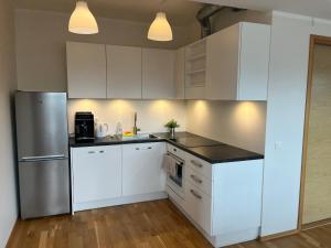 a kitchen with white cabinets and a stainless steel refrigerator at Raatuse 85 Deluxe Apartments in Tartu