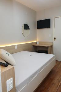 a bedroom with a white bed and a television at Hotel Esperança AdultOnly in Rio de Janeiro