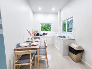 a white kitchen with a wooden table and chairs at Serene Poolvilla hatyai in Hat Yai