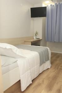 a bedroom with a white bed and a blue curtain at Hotel Esperança AdultOnly in Rio de Janeiro