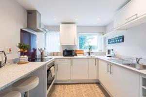 a white kitchen with white cabinets and a sink at Studio near Bristol w/ garden & parking in Flax Bourton