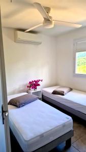 two beds in a room with a ceiling fan at Villa Dézil in Les Anses-dʼArlets +38 photos