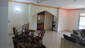 a dining room with a table and chairs and a couch at Serena Beach Road Apartment in Mombasa