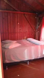 a bed in a room with red wood walls at Cabana 02 superior in Imbituba