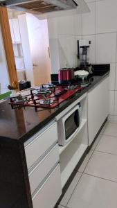 una cocina con estufa y microondas en Sua casa longe de casa, en Samambaia