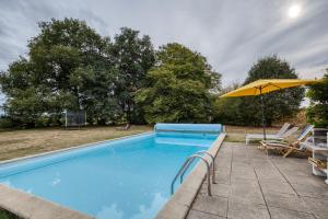 a swimming pool with an umbrella and chairs at La musardière in Saint-Germain-du-Seudre