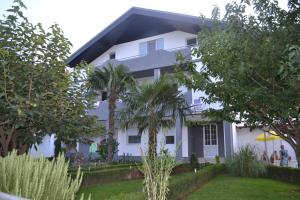 a white house with palm trees in front of it at Apartmani Nino in Star Dojran