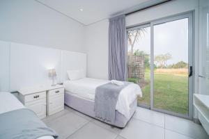 a bedroom with a bed and a large window at 17 Tamboti, Simbithi Eco Estate in Ballito +39 photos