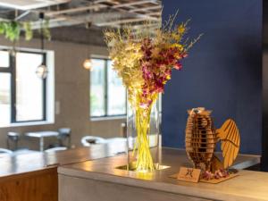 a vase of flowers on a counter with a butterfly at リブマックスホステルズ札幌すすきの in Sapporo