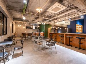a room with tables and chairs and a bar at リブマックスホステルズ札幌すすきの in Sapporo