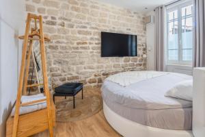 a bedroom with a bed and a tv on a brick wall at Paris Secret Spot - Loft Unique aux portes de Paris in Gentilly
