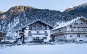 two buildings in the snow in front of a mountain at das Huber in Mayrhofen
