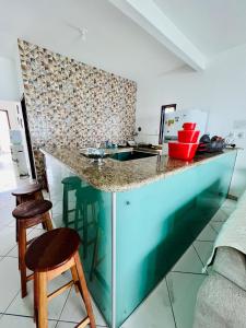 a kitchen with a counter with a sink and two stools at Caminho do Mar in Prado