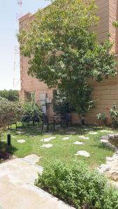 a park with benches and a tree in front of a building at فندق عنيزة الحديث in Unayzah +23 photos