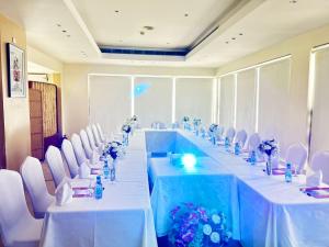 a long table in a room with white chairs at فندق عنيزة الحديث in Unayzah