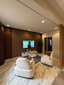 - un salon avec 2 chaises et une télévision murale dans l'établissement logement luxueuse au pieds du monument de la renaissance africaine, à Dakar