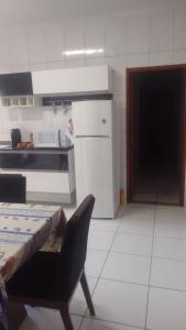 a kitchen with a table and a chair and a refrigerator at Casa Aconchegante in Espirito Santo Do Pinhal