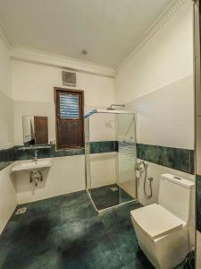 a bathroom with a toilet and a glass shower at Sunrise Palace Negombo in Negombo +42 photos