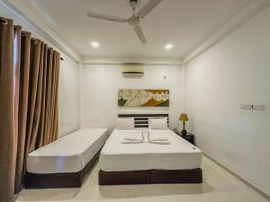 a white bedroom with two beds and a ceiling at Sunrise Palace Negombo in Negombo