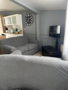 a living room with a couch and a clock on the wall at Le Numéro 1 in Val-Brillant