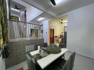 une salle à manger avec une table et des chaises blanches dans l'établissement Fahim Homestay Pasir Mas, à Pasir Mas