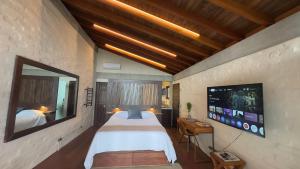 ein Schlafzimmer mit großem Bett und Flachbildfernseher in der Unterkunft Chalé Manacá com vista e pôr do sol in Campos do Jordão